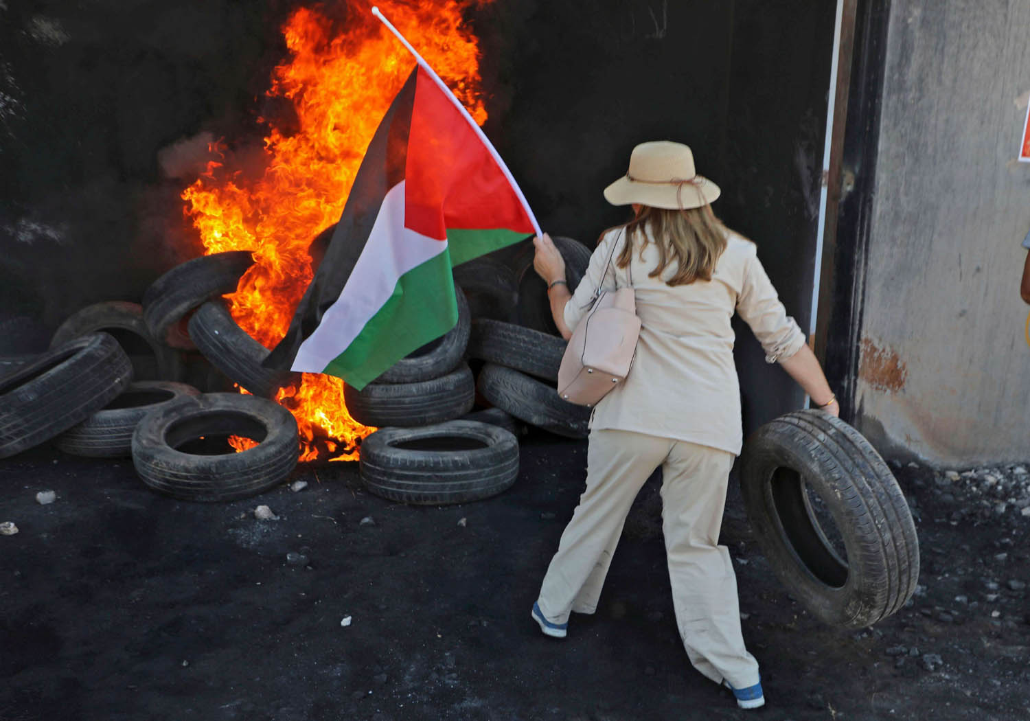 ناشطة غربية ترمي اطارات على كوم يحترق في الضفة الغربية