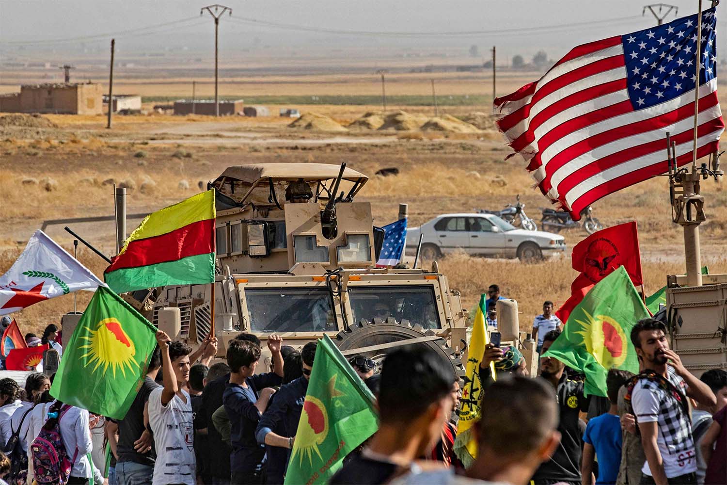 Syrian Kurds gather around a US armoured vehicle during a demonstration against Turkish threats next to a base for the US-led international coalition on the outskirts of Ras al-Ain town in Syria's Hasakeh province 