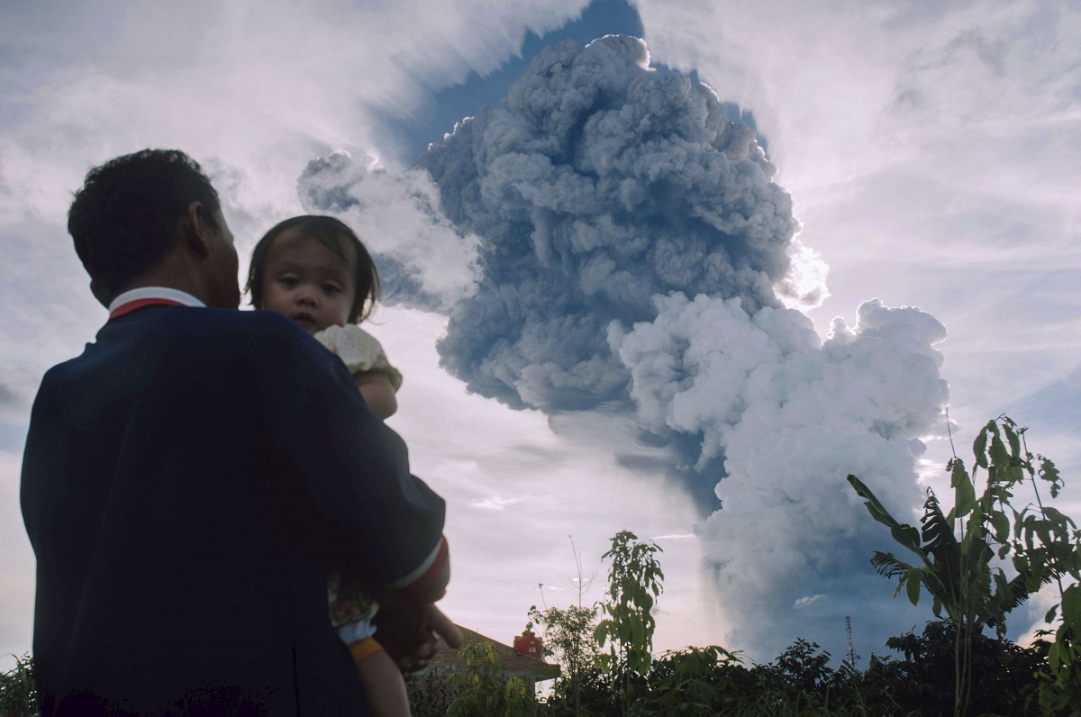 رجل يحمل طفلته يراقب انفجارا بركانيا في اندونيسيا