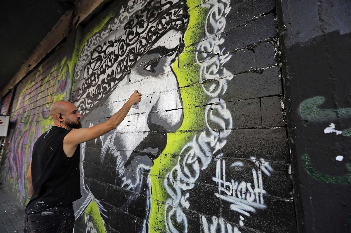 الفنان اللبناني محمد أبرش يرسم على جدار مبنى في ساحة النور في مدينة طرابلس