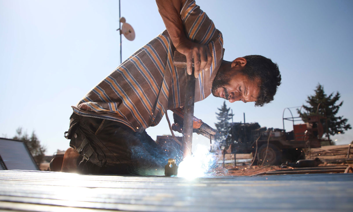 Jumaa al-Mustayf welds metal pipes at a camp for the displaced near the town of Hazano