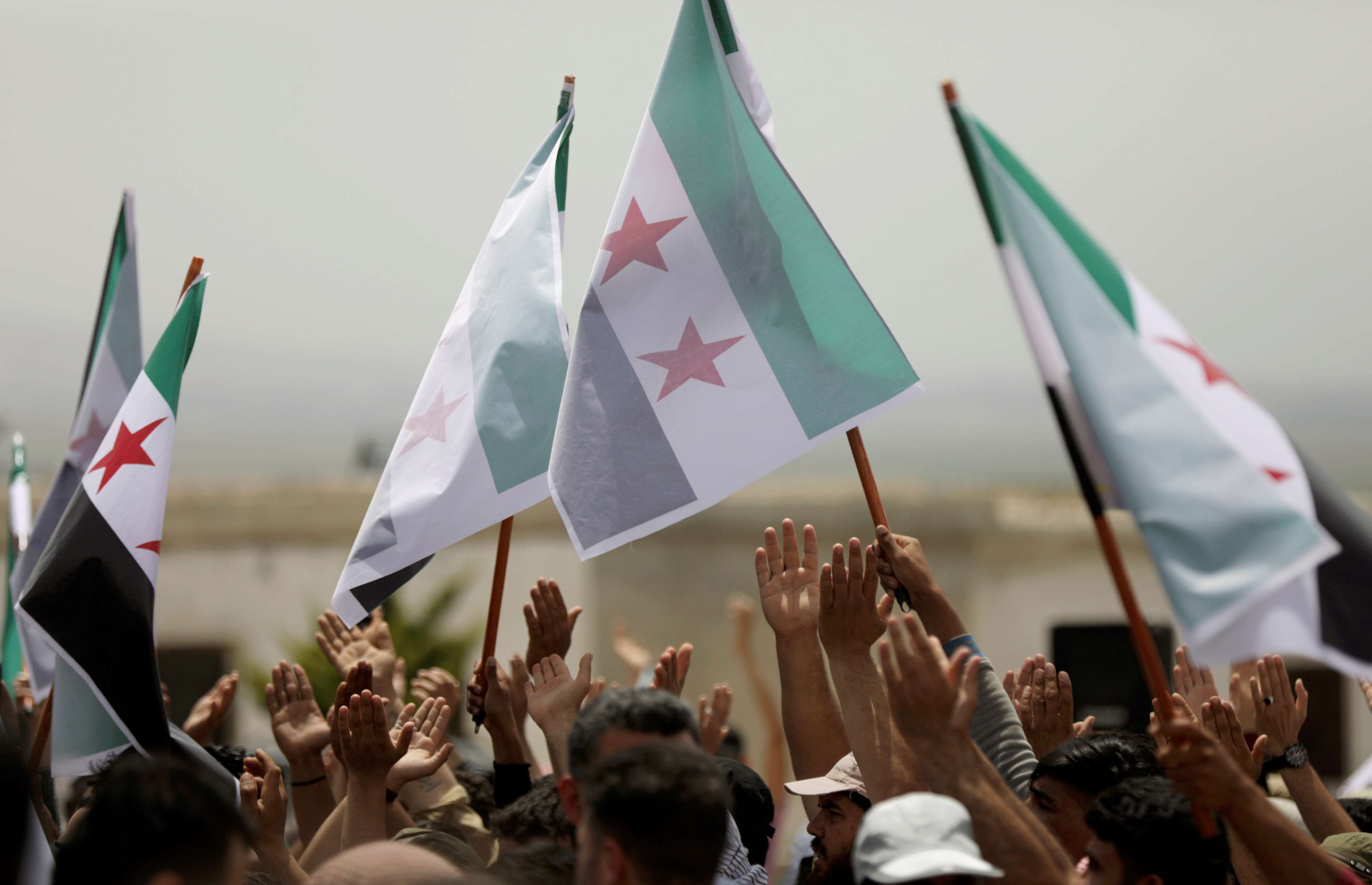 Syrian protesters raise the opposition flag in Idlib province