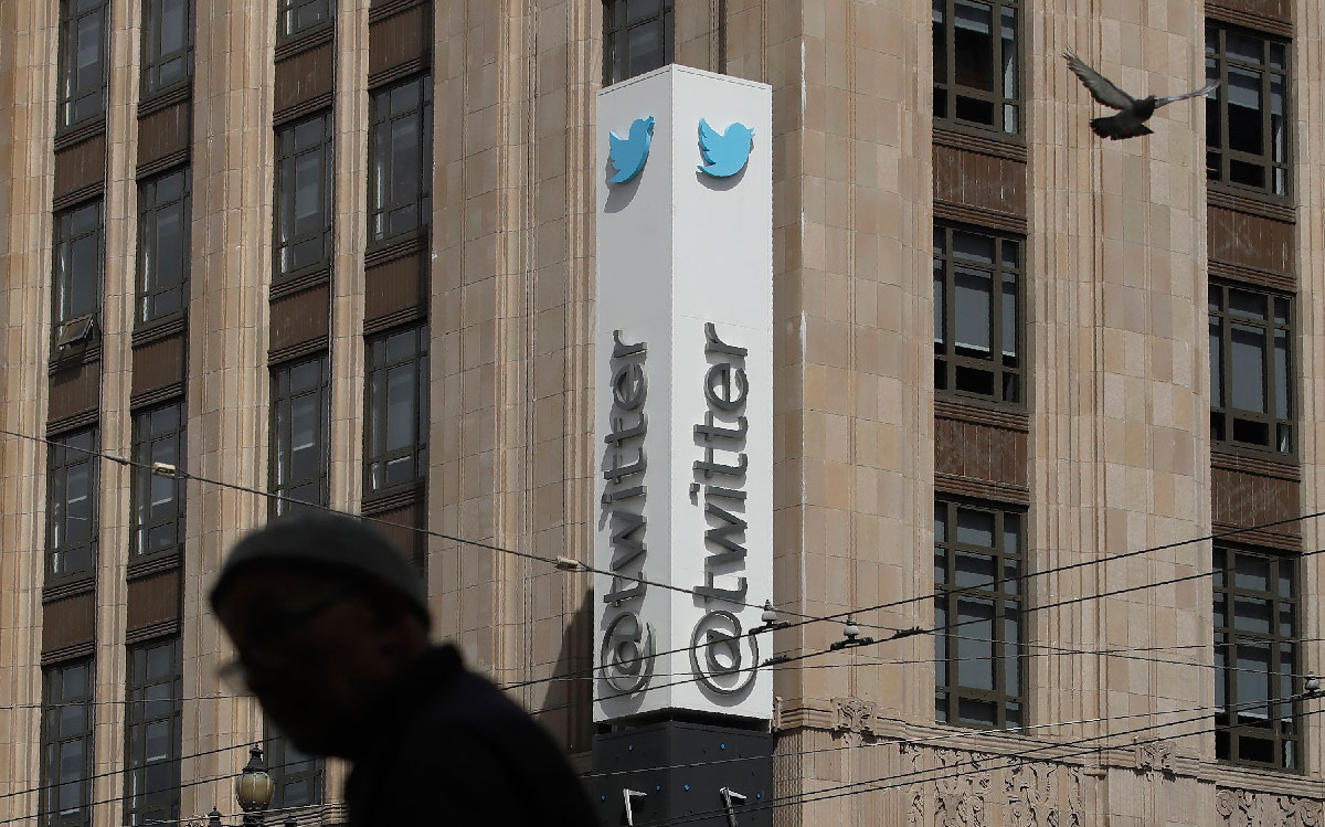 A pedestrian walks across the street from the Twitter office building in San Francisco