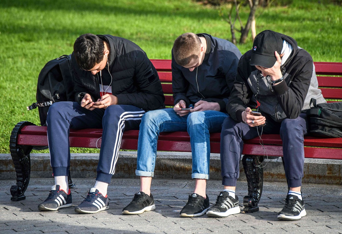 مراهقون روس يستعملون هواتفهم في جلسة بحديقة عامة