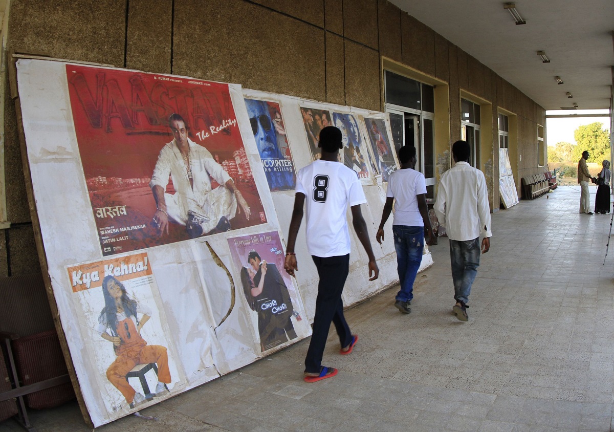رجال سودانيون يمشون عبر ملصقات إعلانية لأفلام في سينما أم درمان في الخرطوم 