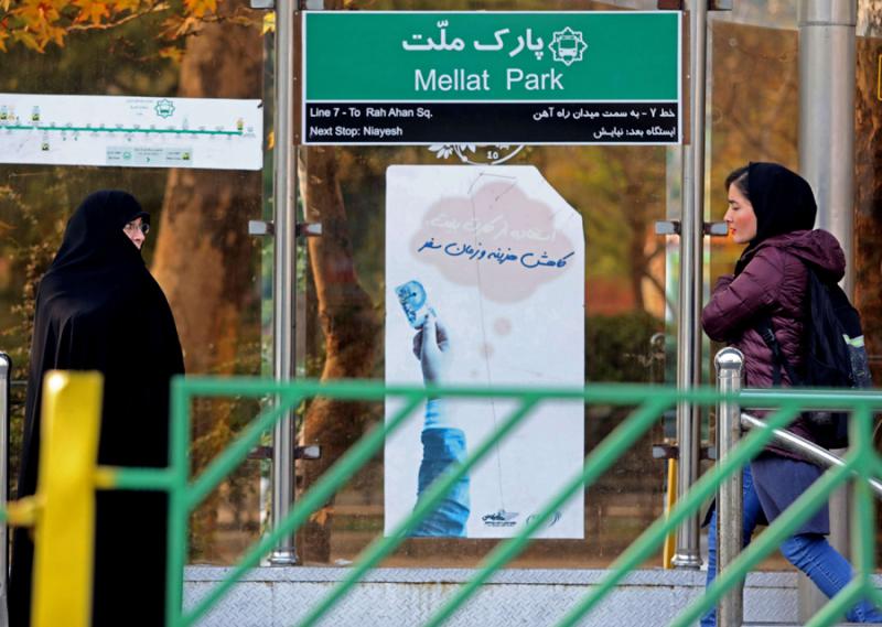 Iranian women walk past a bus station in Tehran
