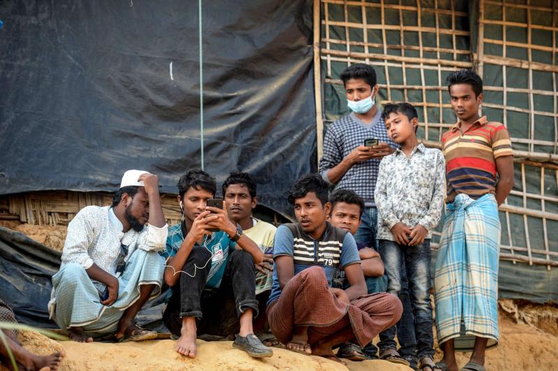 Rohingya refugees watch on a mobile phone a live feed of Myanmar's State Counselor Aung San Suu Kyi's appearance at the UN's International Court of Justice in the Hague