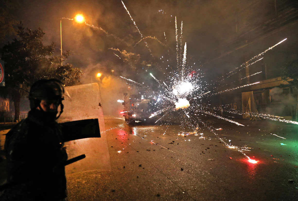 Supporters of Lebanon's Shiite Hezbollah and Amal groups hurl fireworks at security forces in Beirut