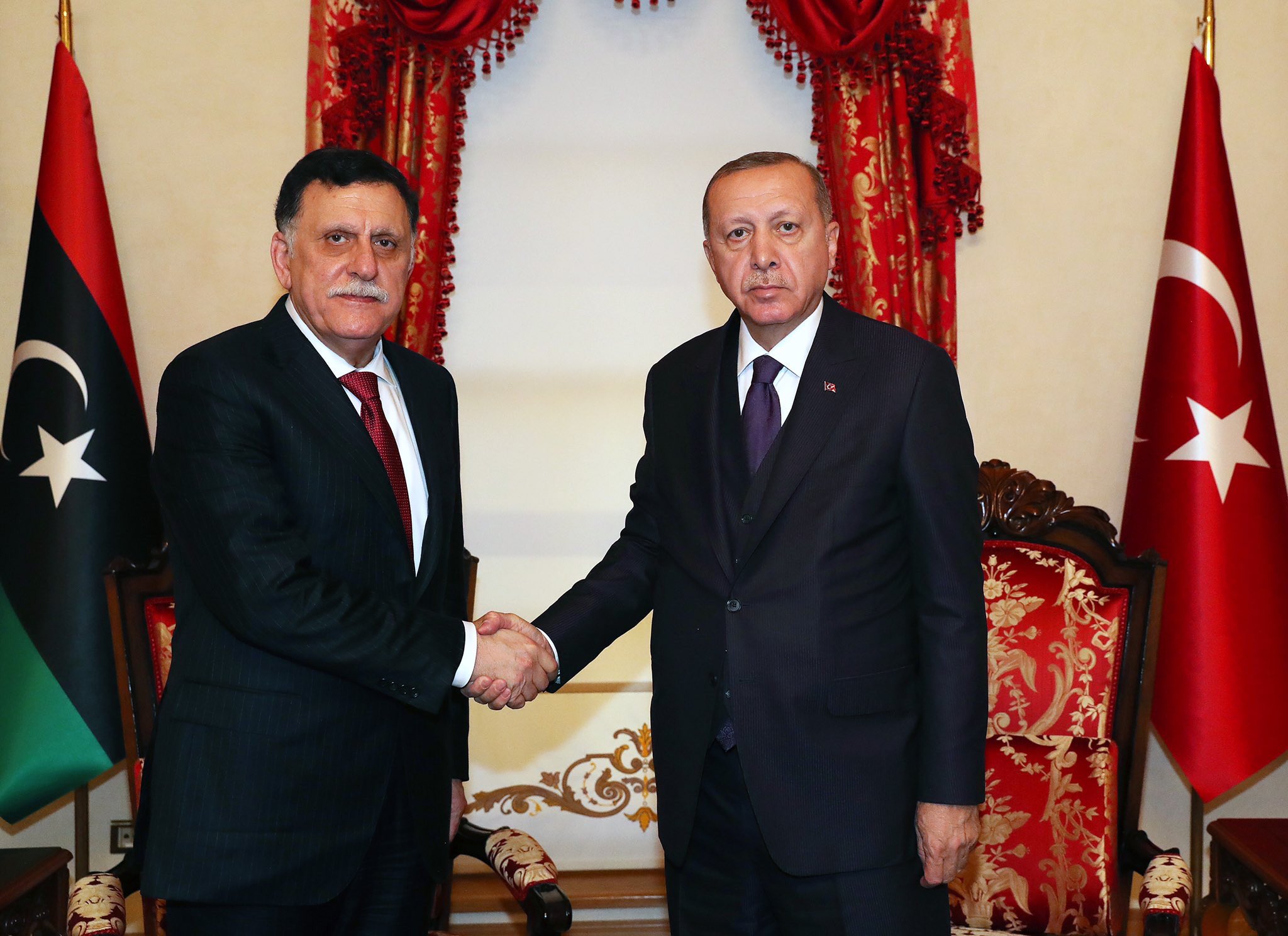 Turkish President Recep Tayyip Erdogan (R) shakes hands with head of Libya's UN-backed government, Fayez al-Sarraj