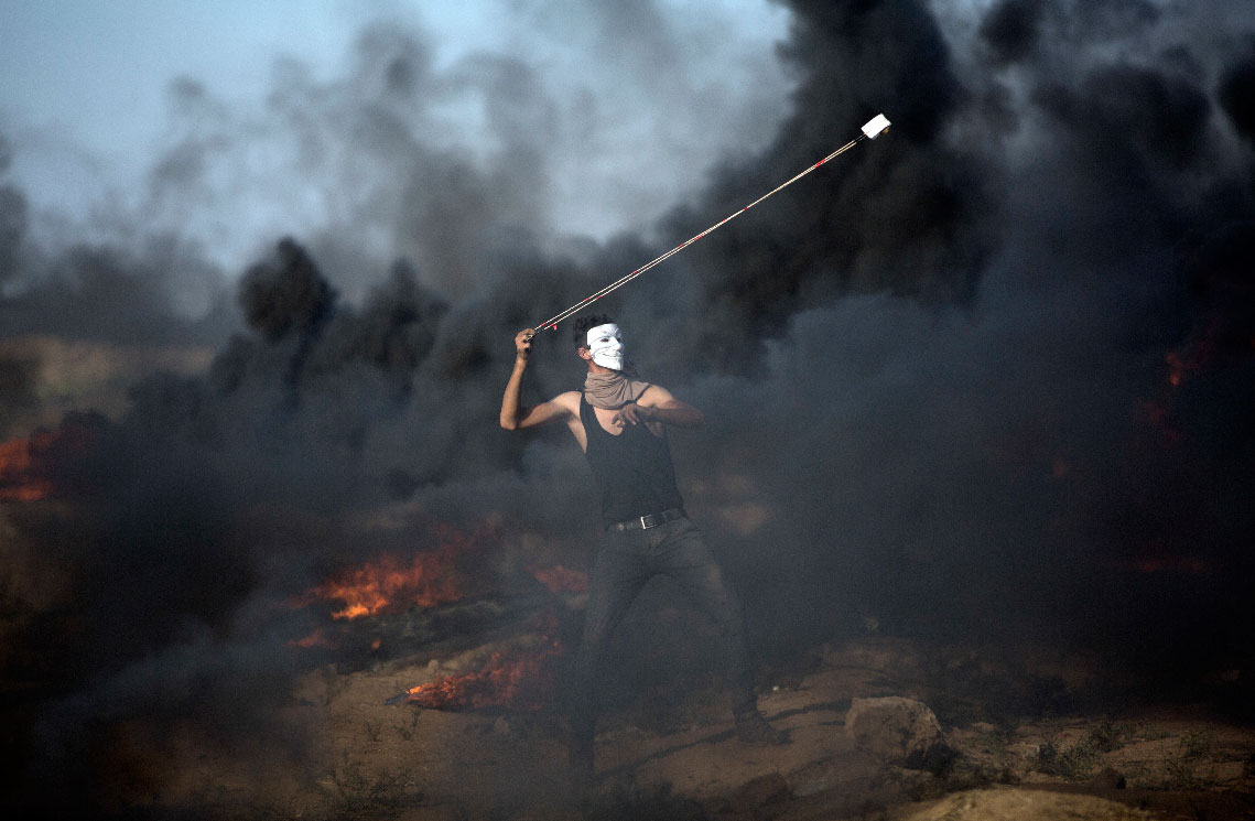 A Palestinian protester hurls stones at Israeli troops during a protest in Gaza