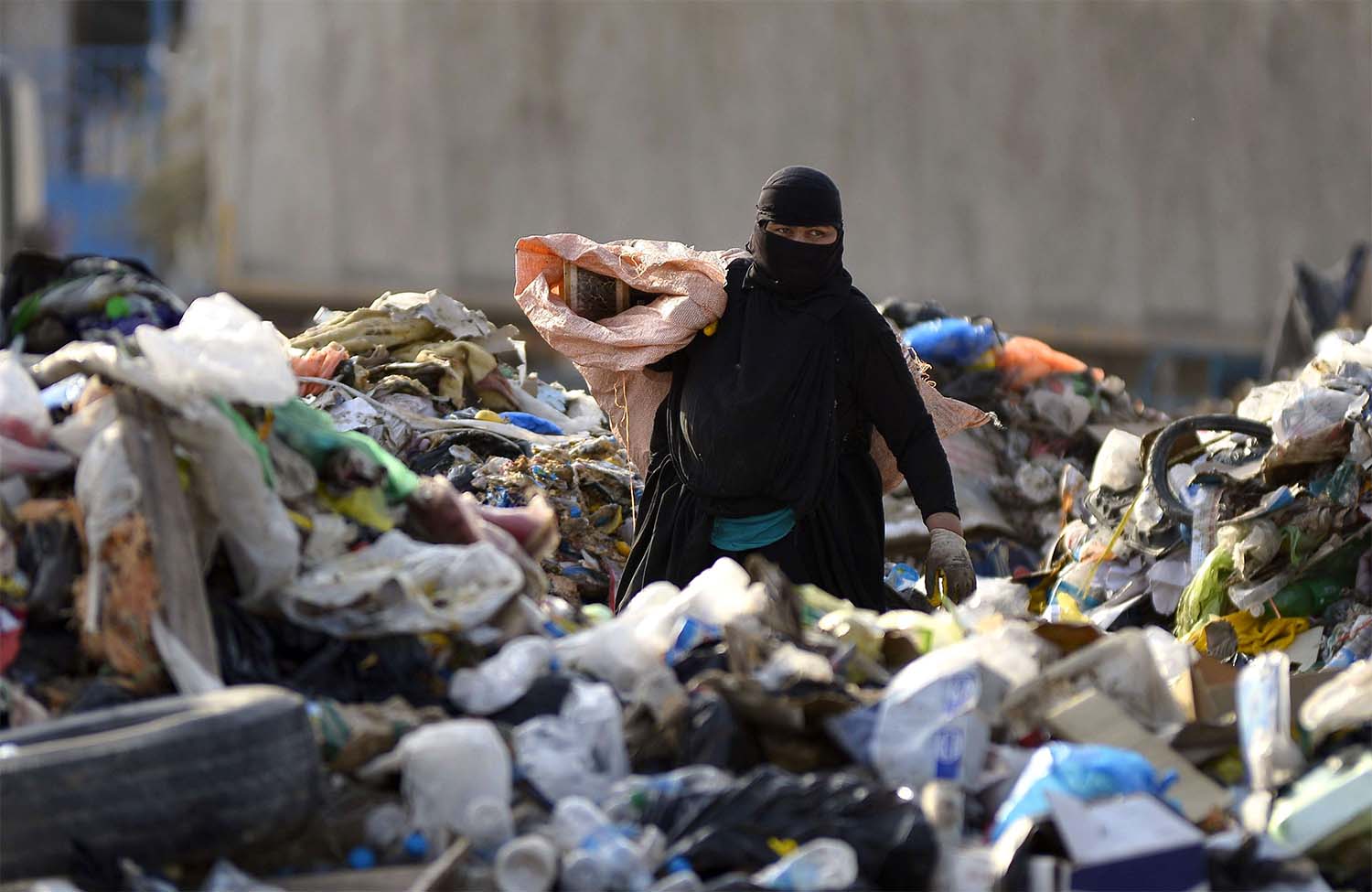 A woman collects recyclable items at a landfill to be sold for extra income in the Iraqi holy city of Najaf 