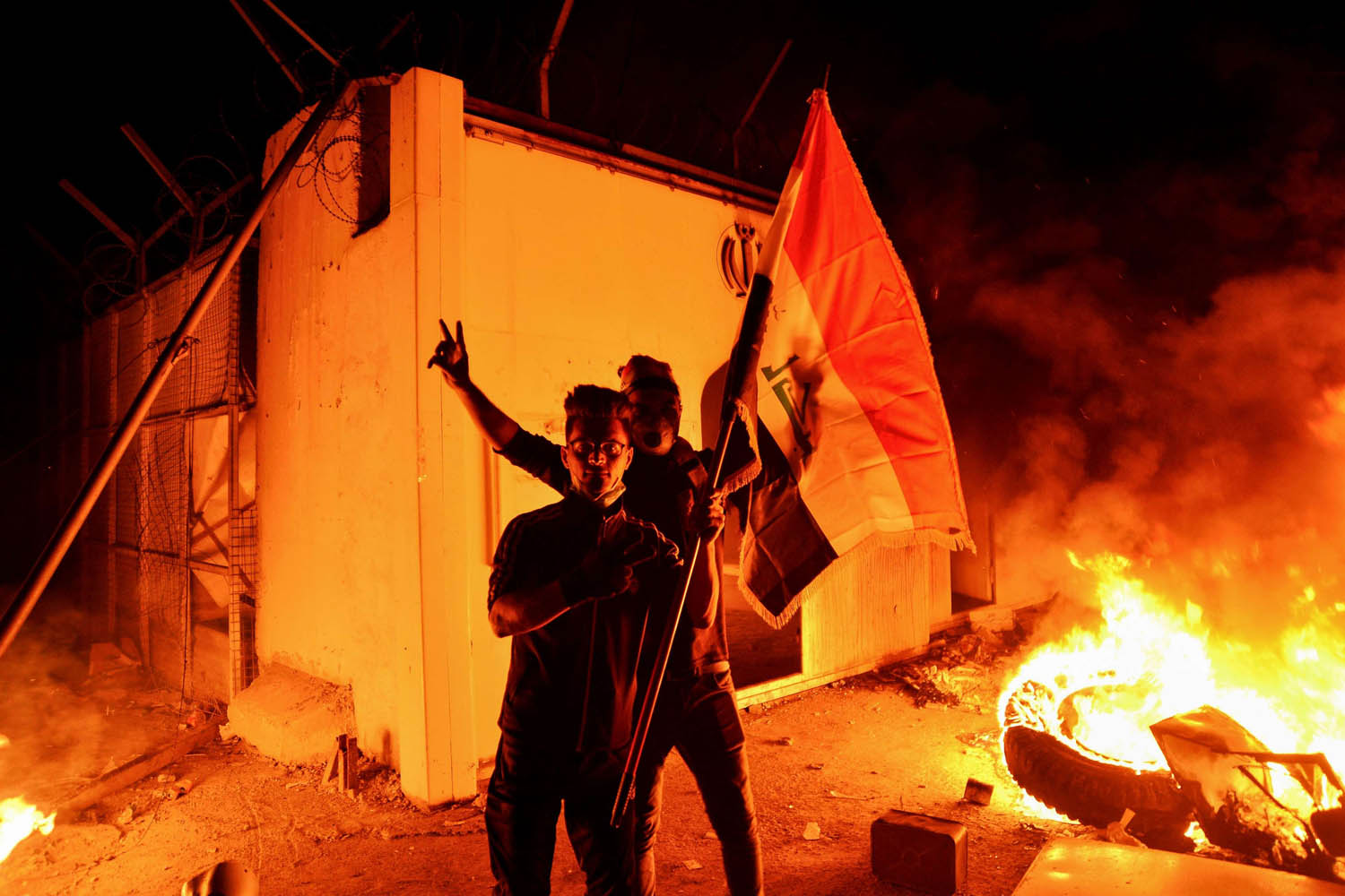 متظاهرون عراقيون يقفون امام حرائق القنصلية الإيرانية في النجف