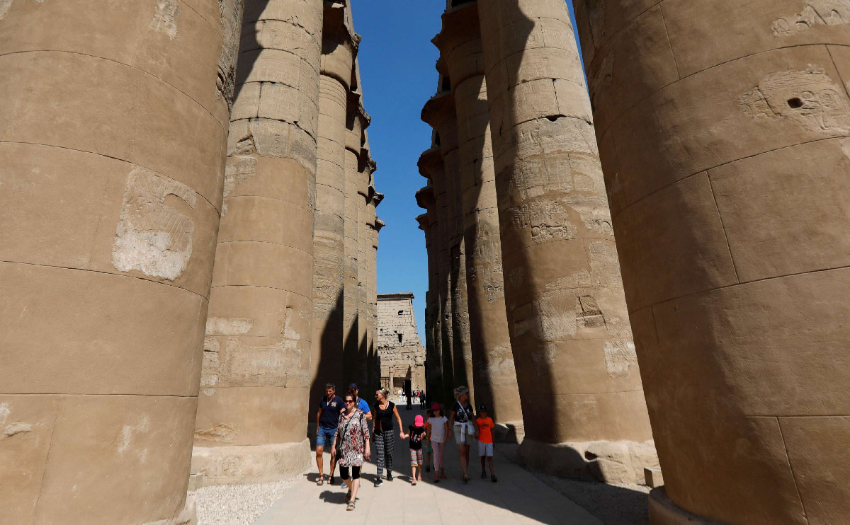 Tourists walk through columns at the site of Luxor Temple in Luxor, Egypt