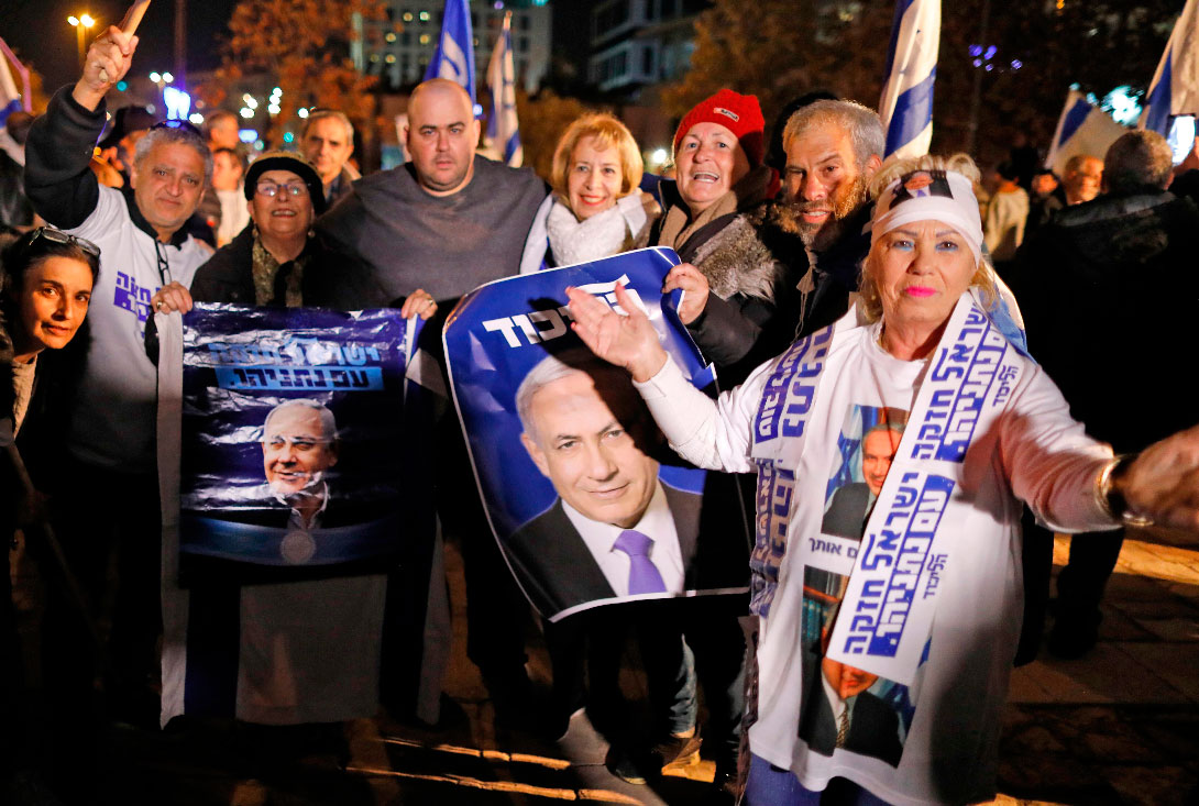 Israelis gather signs showing portraits of Israeli Prime Minister Benjamin Netanyahu