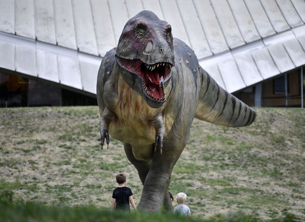 طفلان يقفان أمام نسخة طبق الأصل بالحجم الطبيعي من التيرانوصور ريكس في معرض بألمانيا