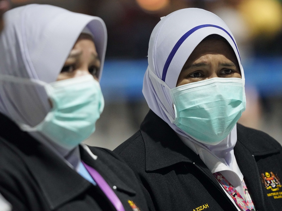 مسؤولتان عن الصحة ترتديان أقنعة الوجه في مطار كوالالمبور الدولي 