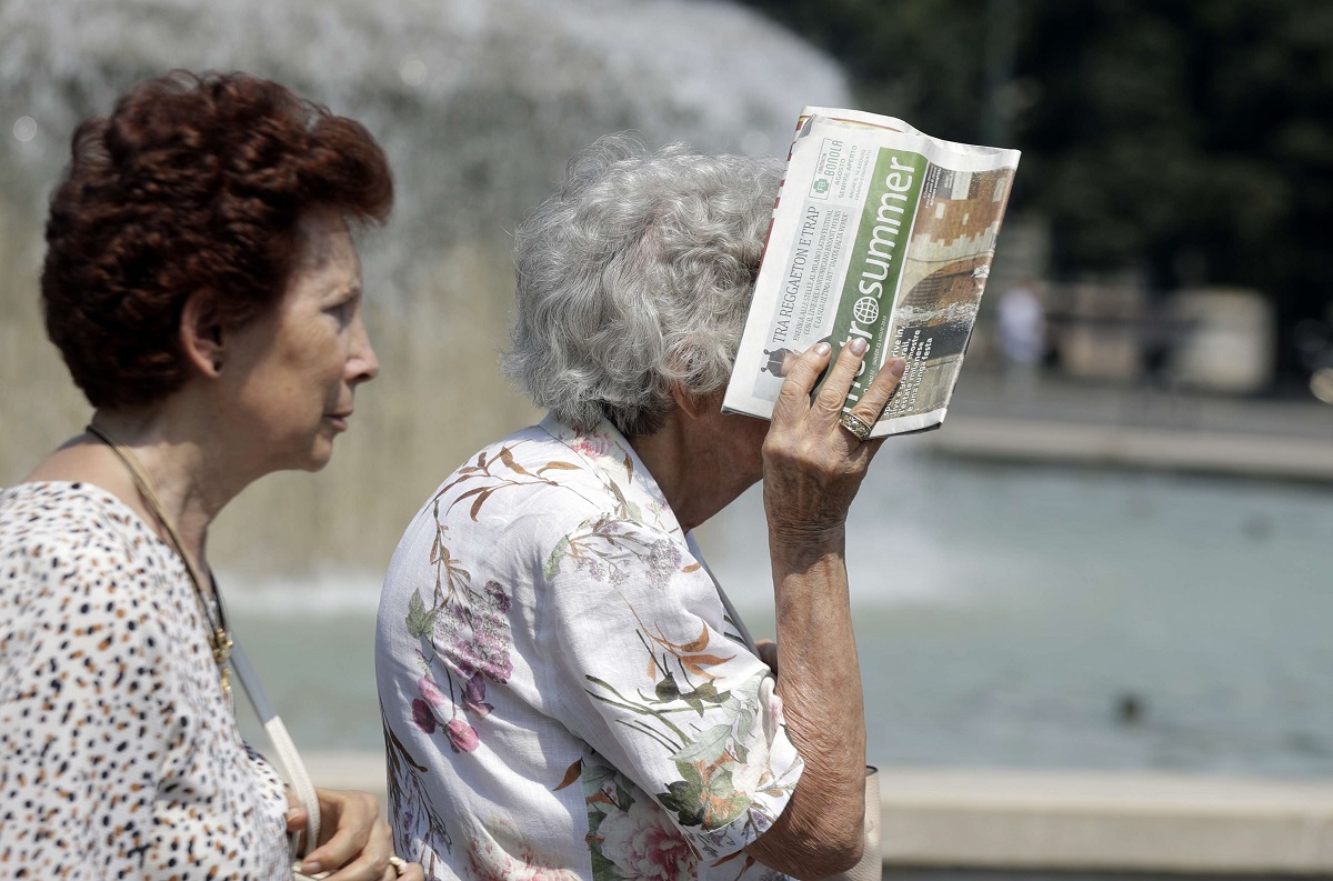 سيدة مسنة تغطي وجهها من أشعة الشمس الحارقة بصحيفة في ميلانو بإيطاليا في صيف 2019