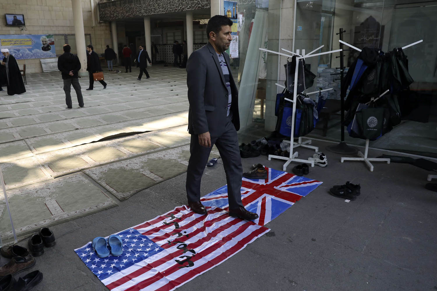 ايراني يمر على علمي الولايات المتحدة وبريطانيا في قاعة لمسجد يستضيف تأبينا لقاسم سليماني