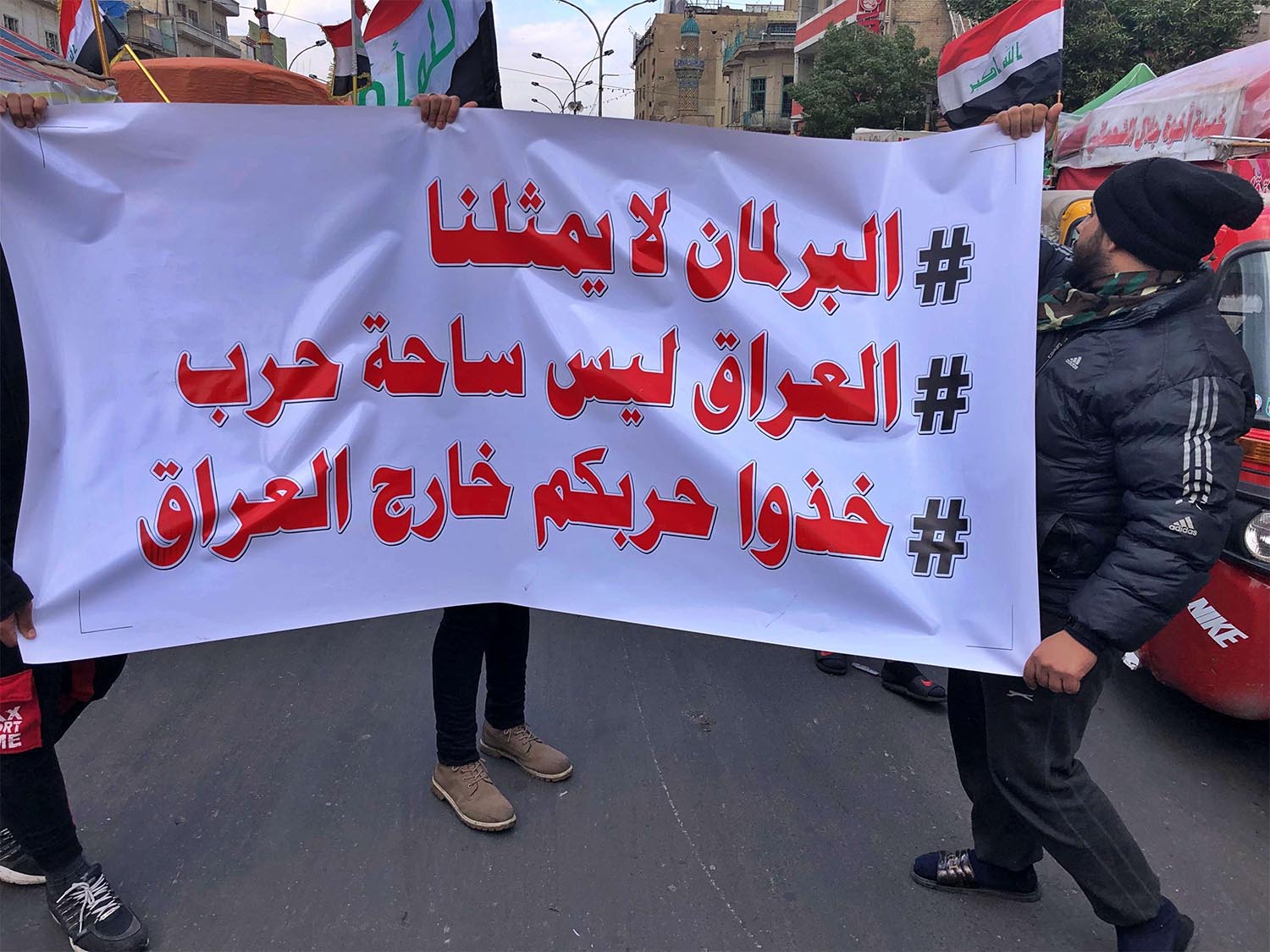 Protesters hold a banner with Arabic that reads, "Parliament does not represent me, Iraq is not a battlefield, and Take your war outside Iraq" during a sit-in at Tahrir Square in Baghdad