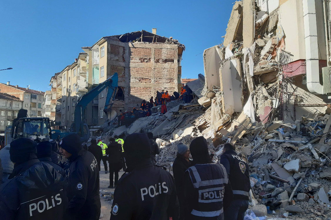 Turkish officials and police work at the scene of a collapsed building in Elazig, Turkey