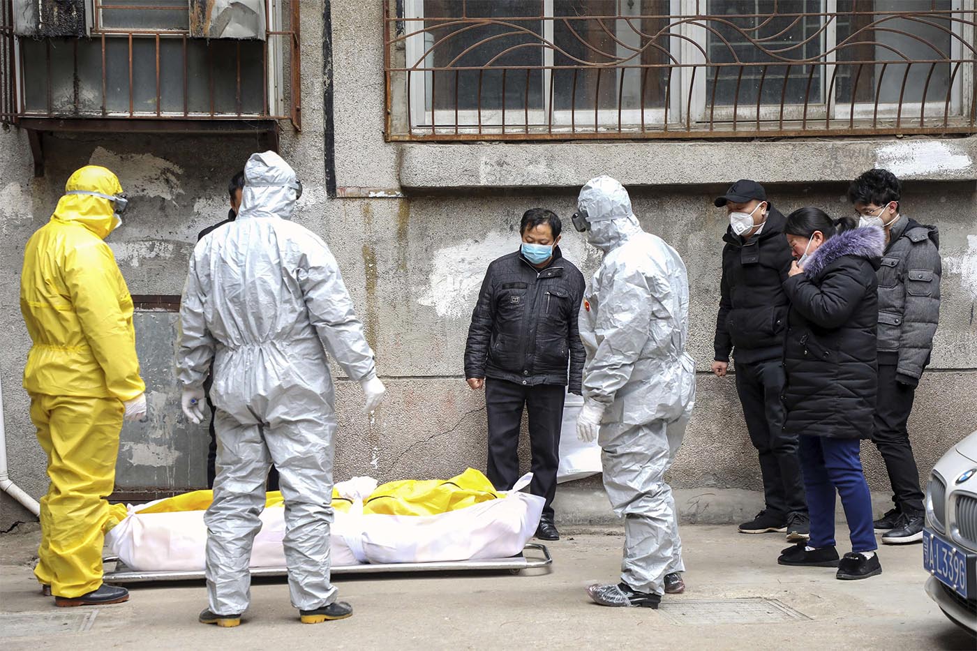 Funeral home workers remove the body of a person suspect to have died from a virus outbreak from a residential building in Wuhan 