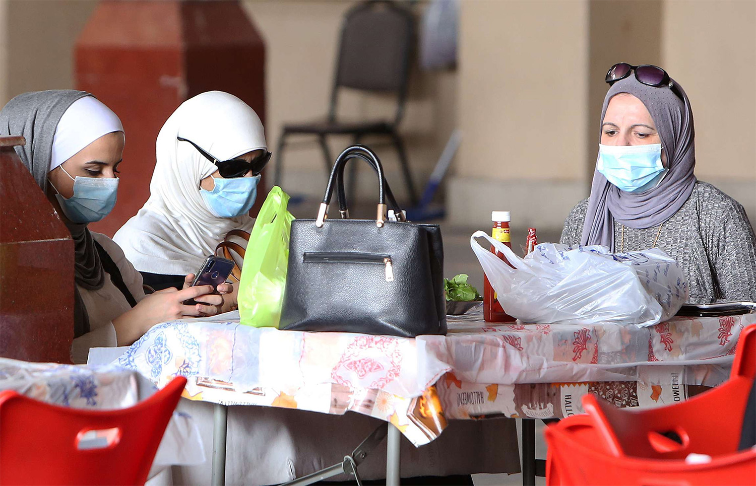 Kuwaiti women wear protective masks as they sit in a restaurant inside the Mubarakiya Market in Kuwait City 