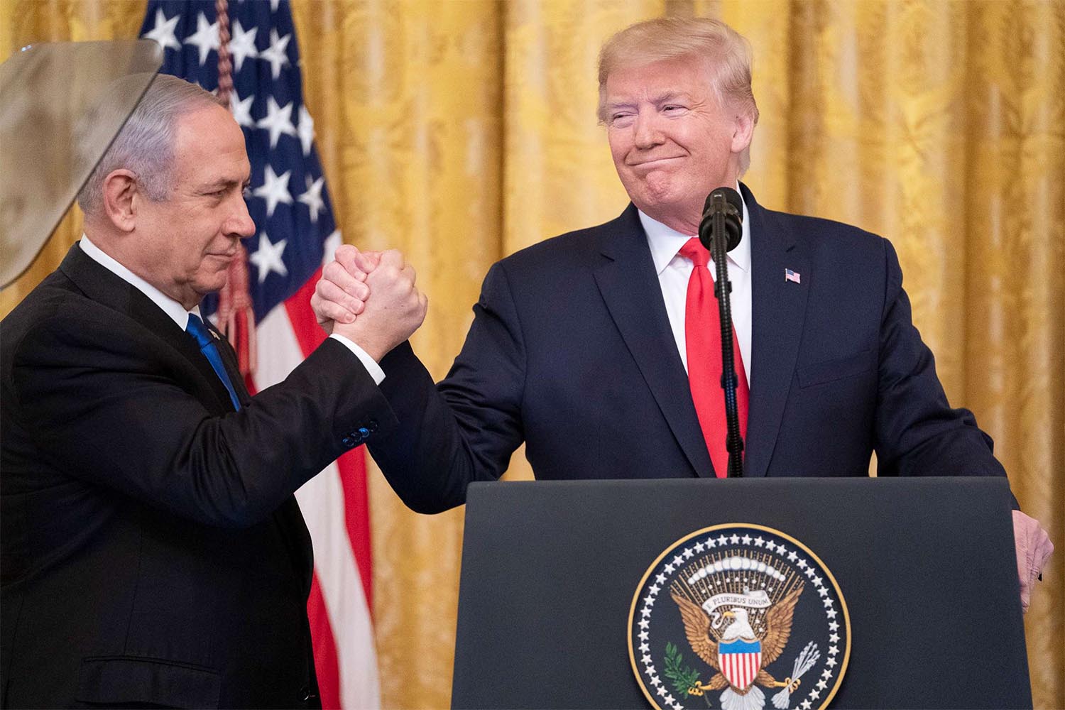 Israeli Prime Minister Benjamin Netanyahu and US President Donald Trump hold hands at the end of a joint press conference to announce the US' Middle East peace plan proposal