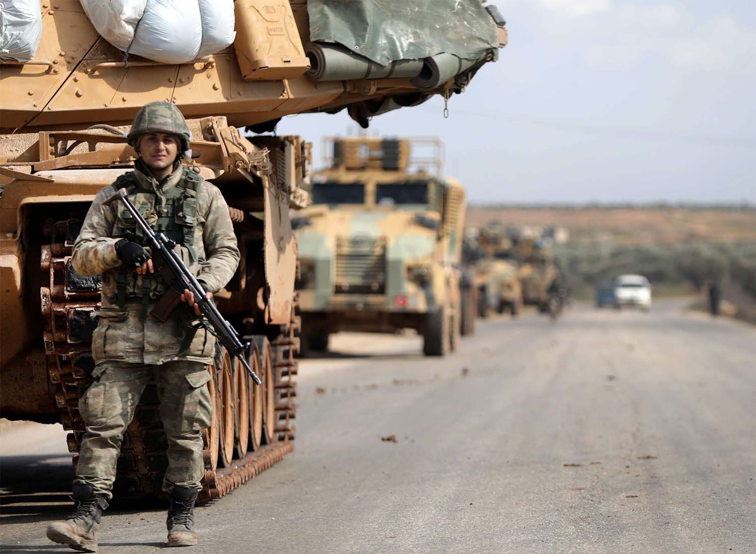 Turkish soldier stands in front of a military vehicles convoy east of Idlib city in northwestern Syria 