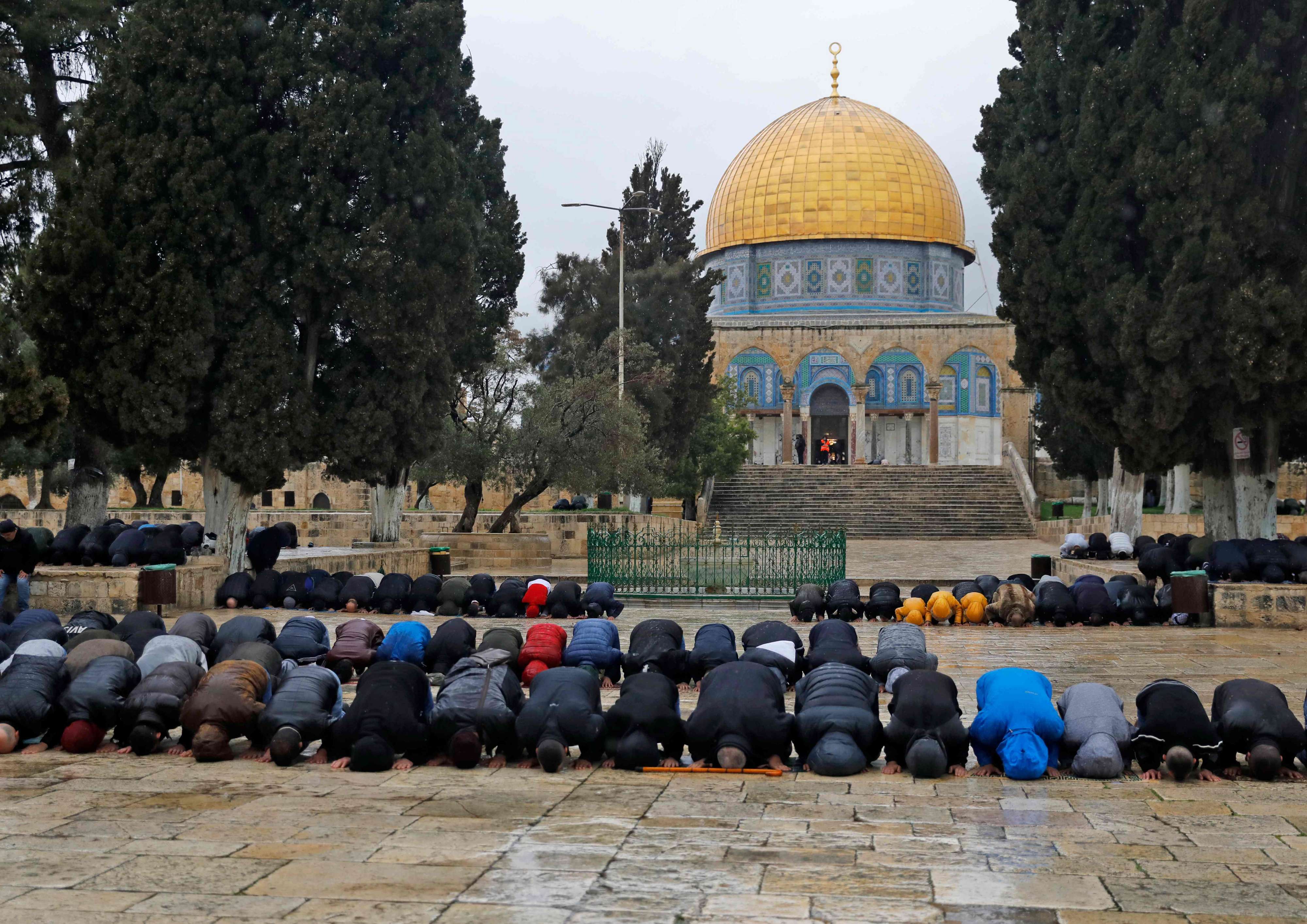 Muslim worshipers pray in a courtyard of the Al-Aqsa mosque compound, with the Dome of the Rock in the background