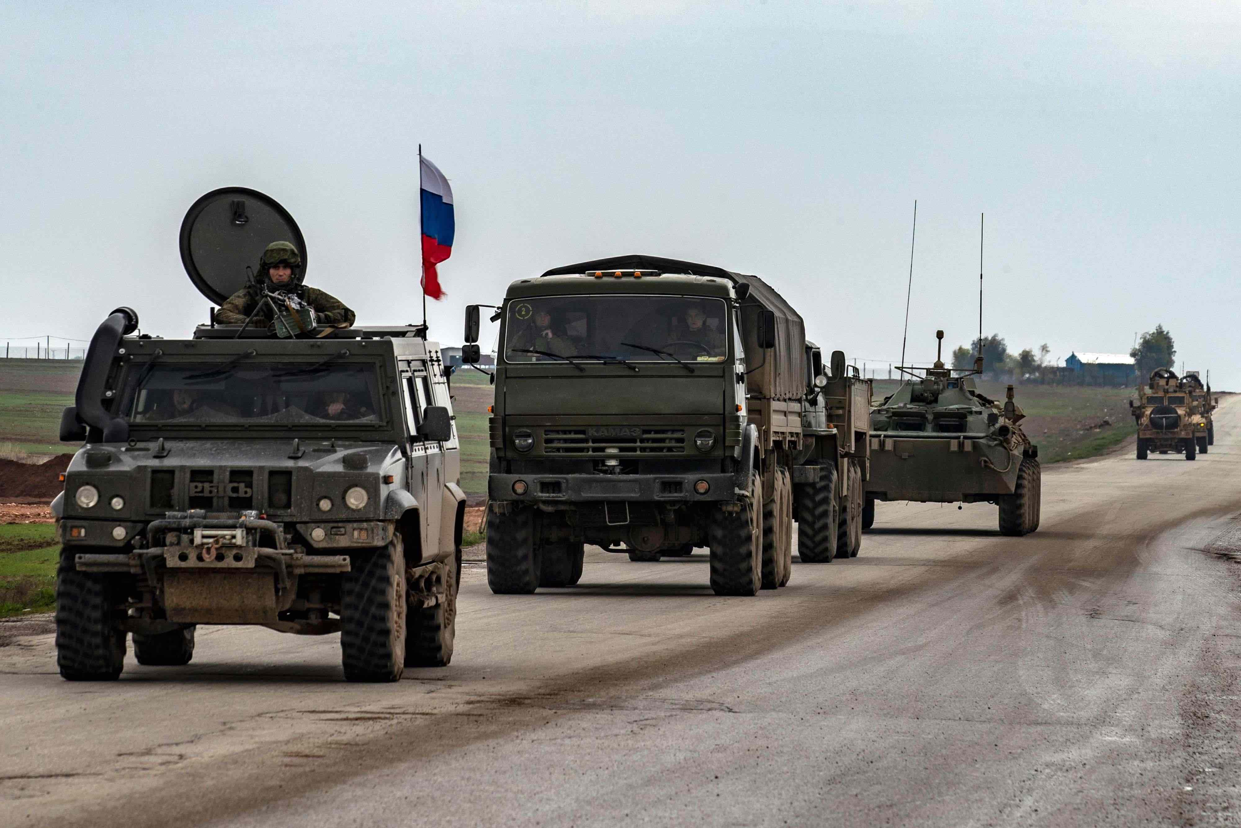 A Russian military convoy is seen in front of a US military convoy on the key M4 highway in Syria's northeastern Hasakeh province