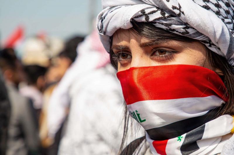 An Iraqi demonstrator covering her face with the national flag looks on during an anti-government demonstration by Basra University students