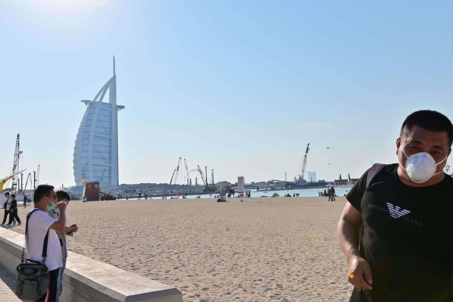 Tourists wearing surgical are pictured on a beach next to Burj Al Arab