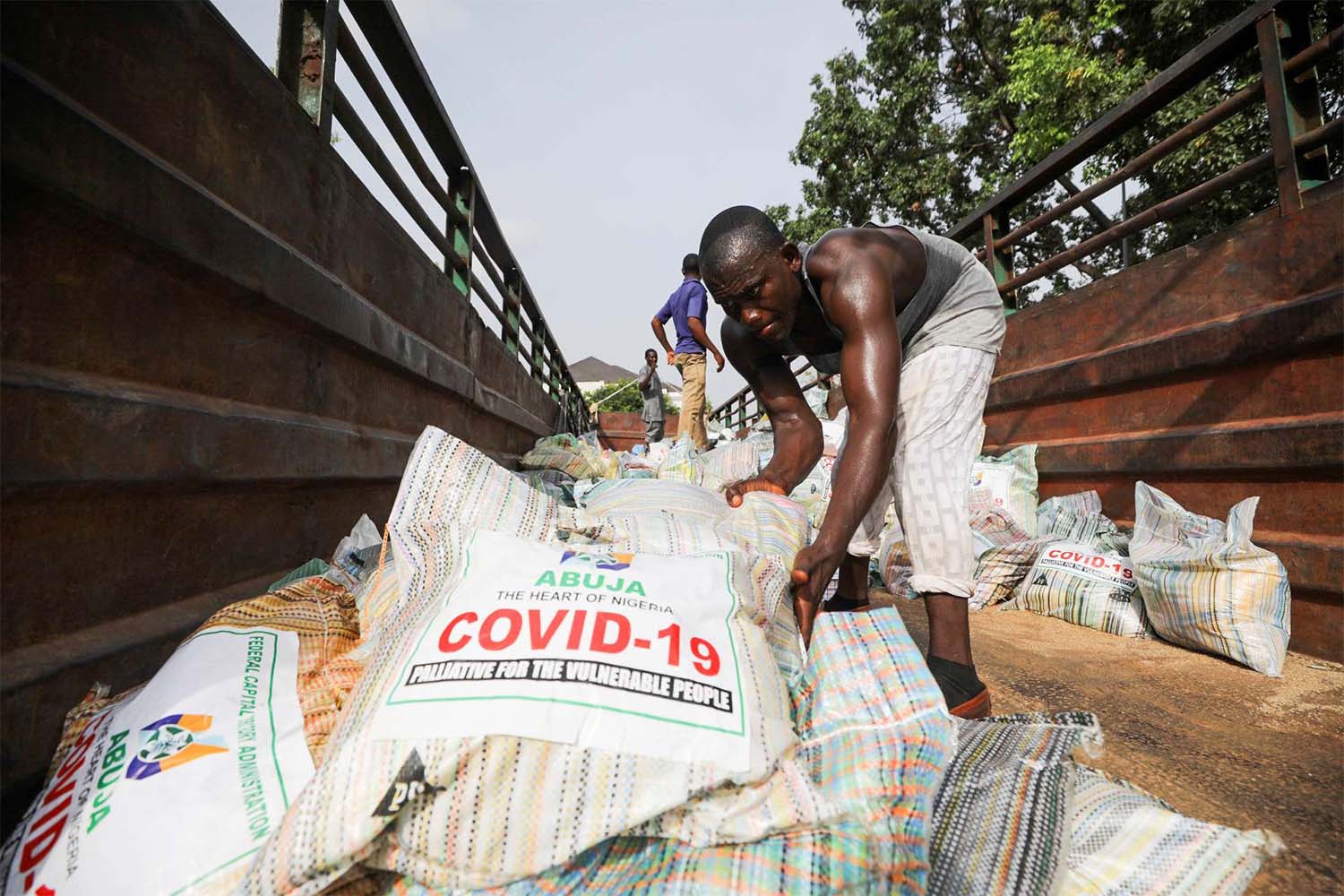 Men load sacks of rice among other food aid in a truck, to be distributed for those affected by procedures taken to curb the spread of coronavirus in Abuja