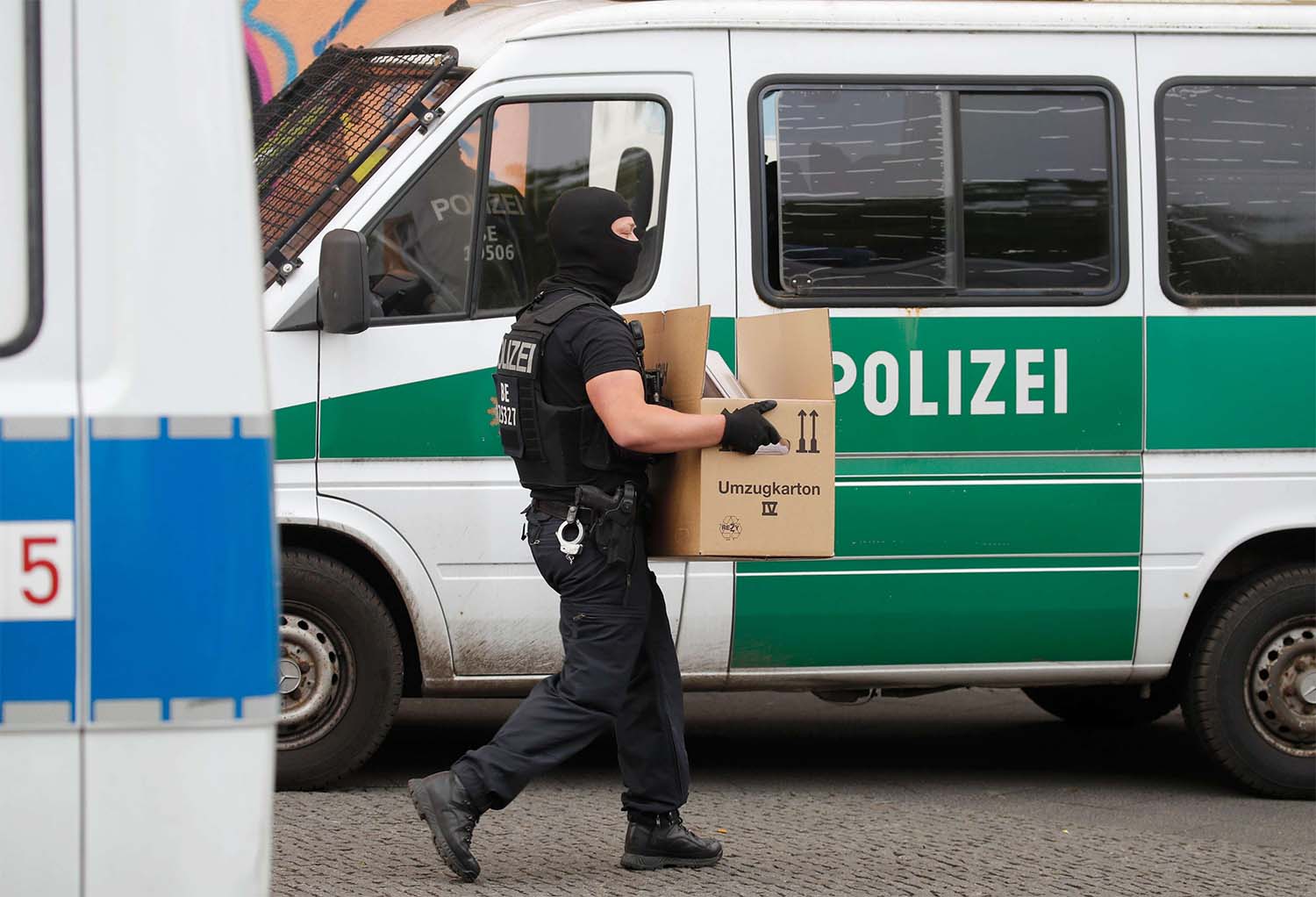 Police carry evIdence in a moving box out of Al-Irschad Mosque during a raid in Berlin