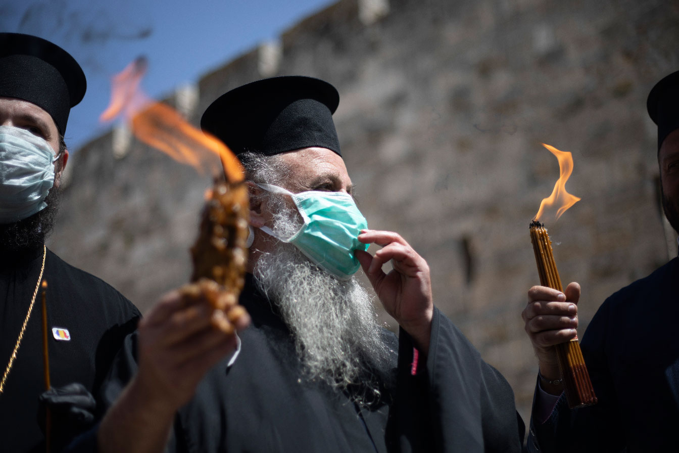 Orthodox clergymen hold candles lit from fire of the Church of the Holy Sepulchre