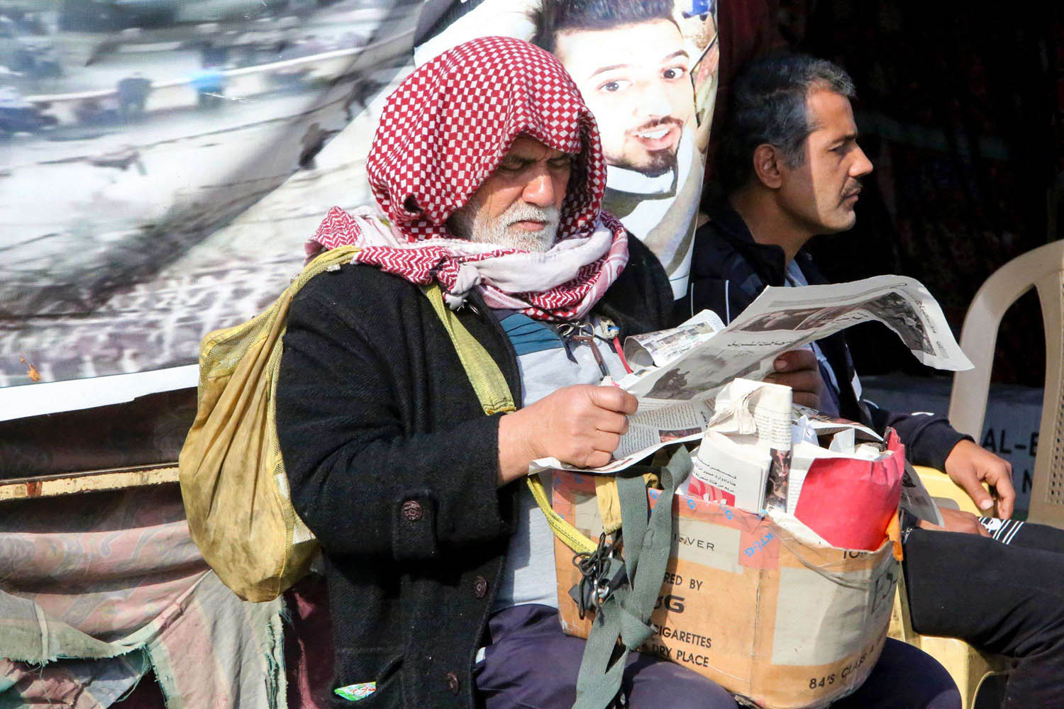 عراقي يتصفح جريدة في ساحة الاحتجاجات وسط بغداد