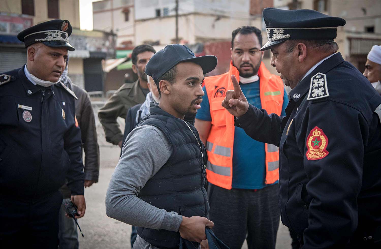 Moroccan policeman, patrolling as part of a larger combined security force, instructs a man to return home