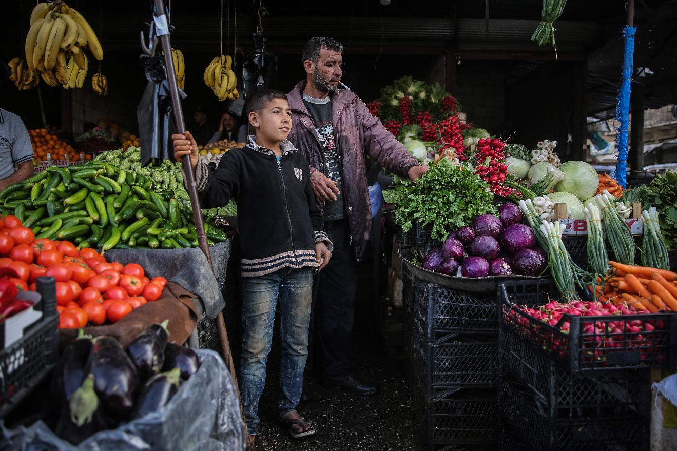 Syrians buy fresh vegetables at a street market