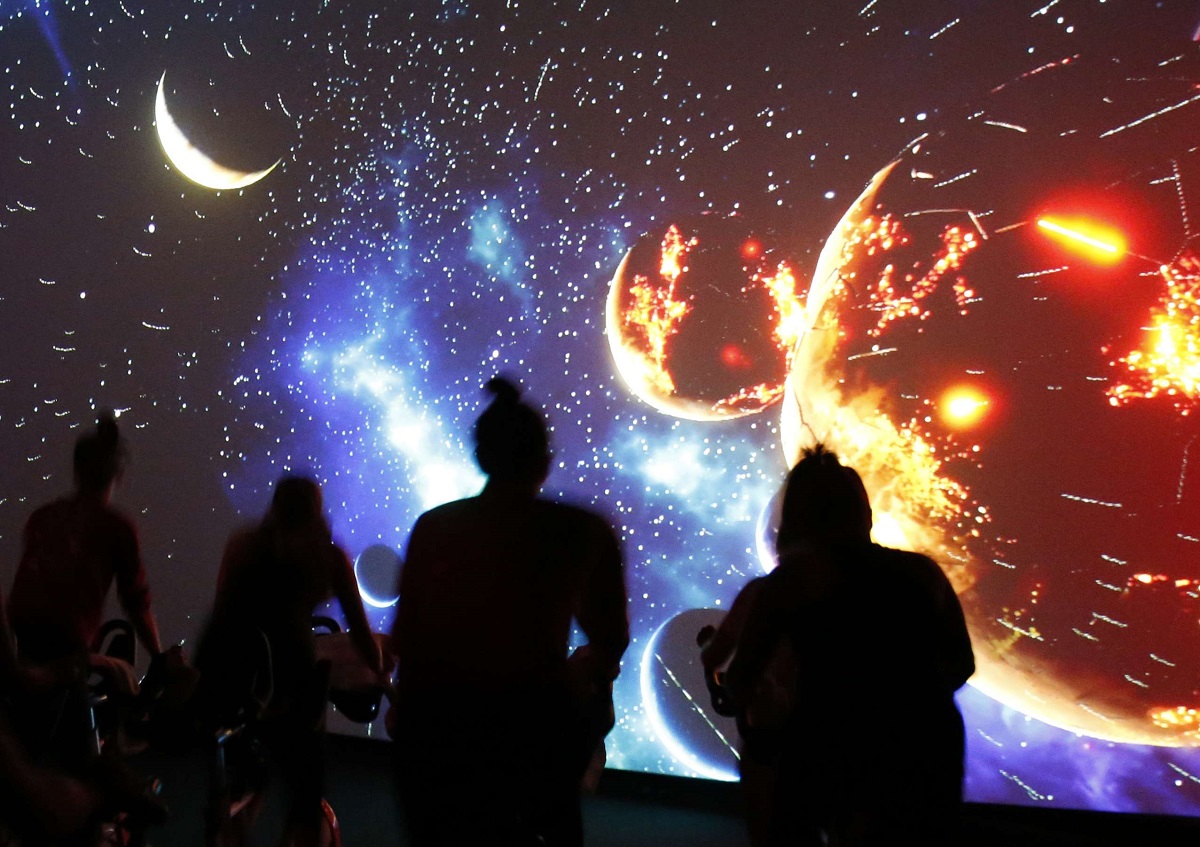 أشخاص ينظرون إلى صورة للنظام الشمسي تظهر على شاشة ضخمة في بروكلين في نيويورك