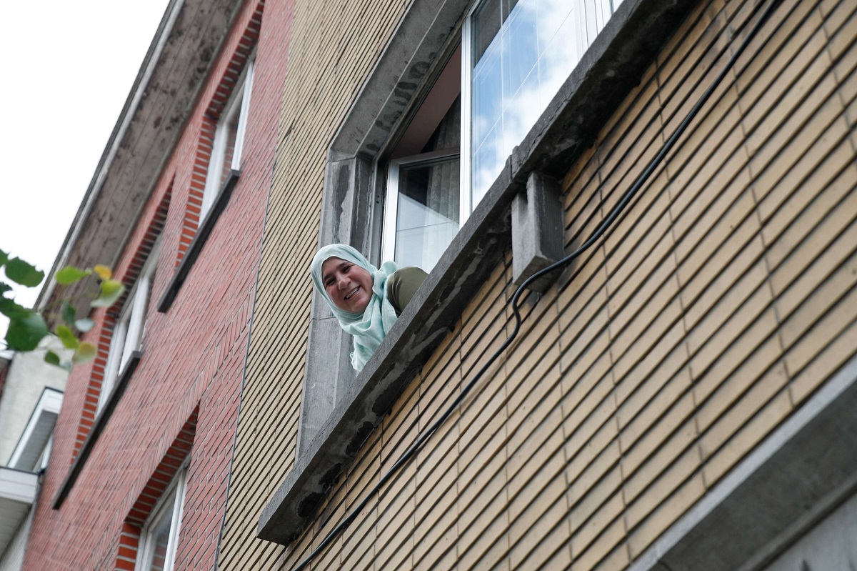 امرأة عربية تطل من نافذة شقتها في بروكسل