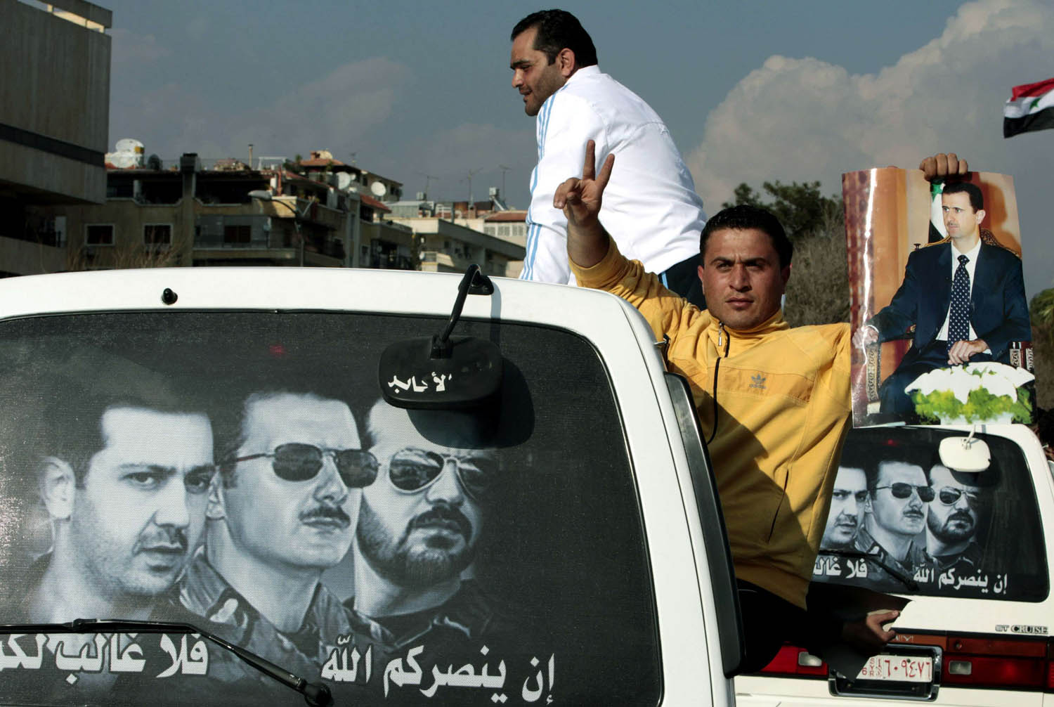 ملصق يجمع الرئيس السوري بشار الأسد مع أخيه ماهر والراحل باسل الأسد