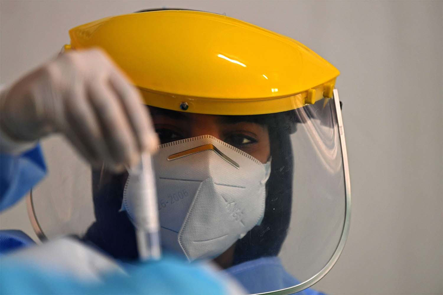 A health worker looks at a sample taken from a foreign worker to check for the novel coronavirus at a testing centre in the Al Quaz area of Dubai