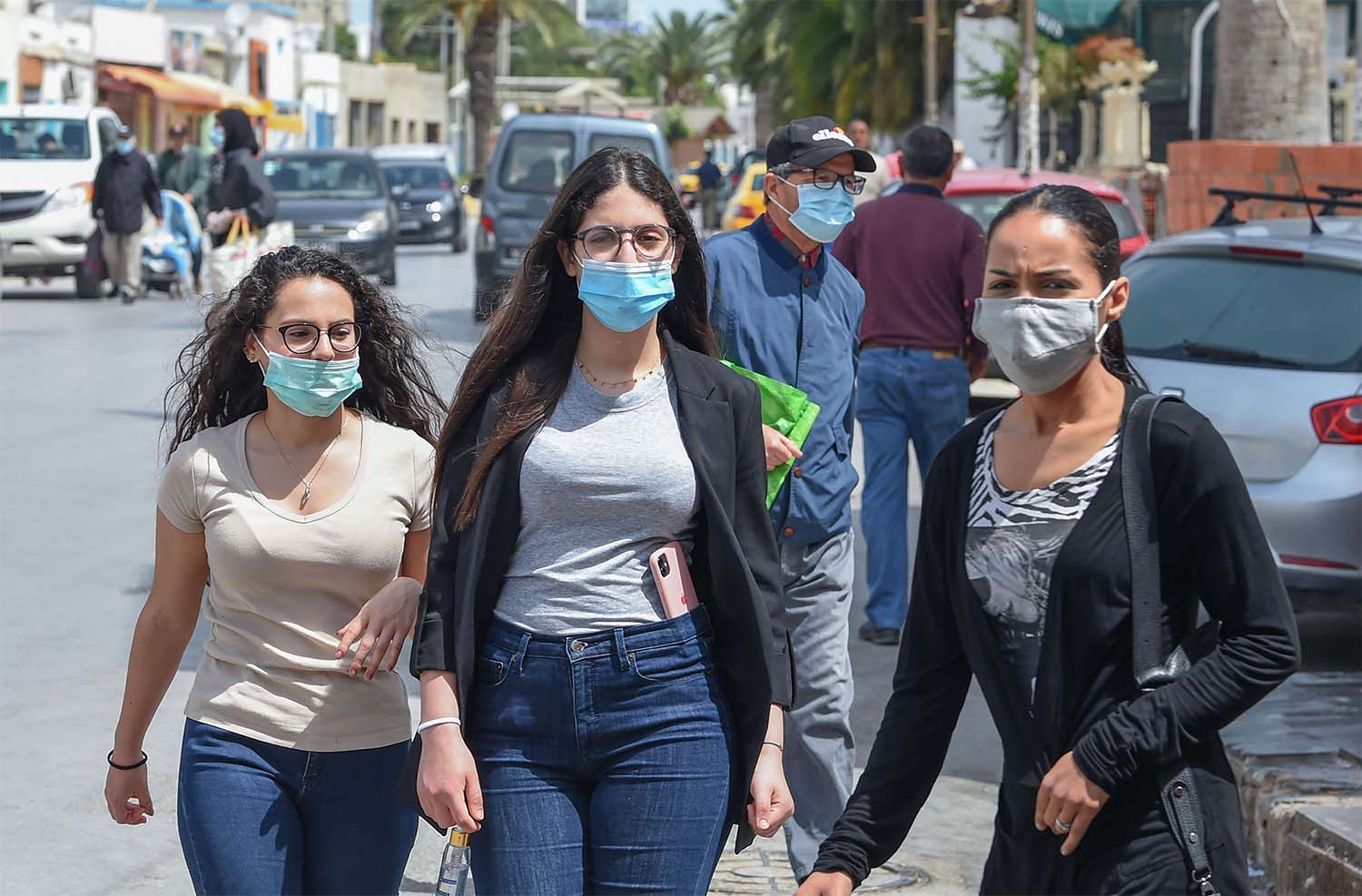 Tunisians wearing protective masks amid the COVID-19 pandemic walk by 