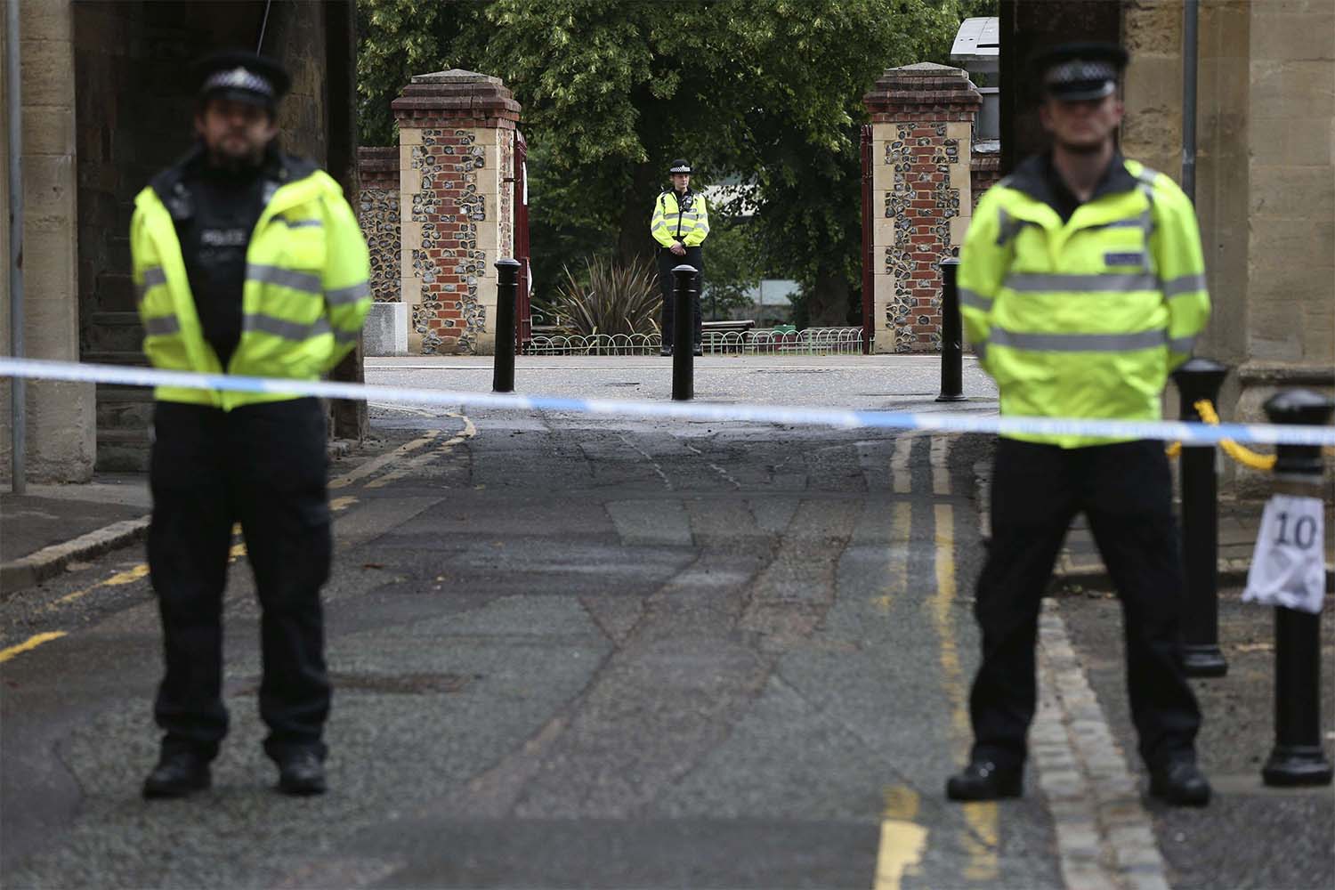 Police stand guard at the Abbey gateway of Forbury Gardens park in Reading town centre following Saturday's stabbing attack in the gardens