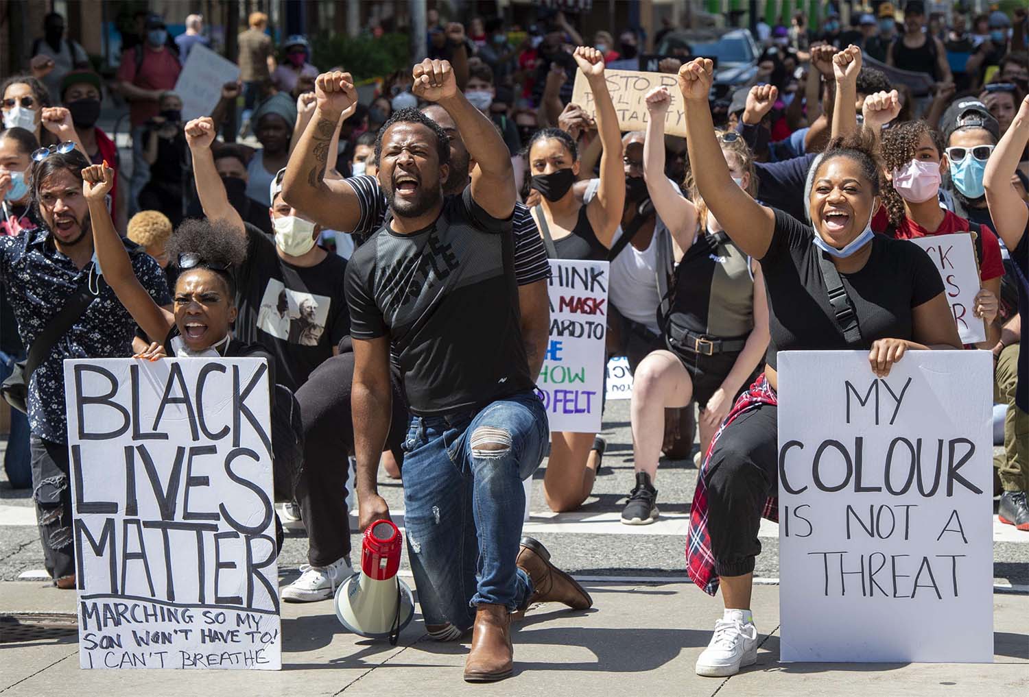 Anti-racism demonstrators take a knee near Toronto Police Headquarters during a march on Saturday, June 6, 2020, protesting the death of George Floyd