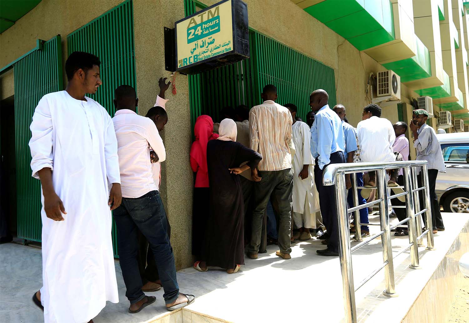 People queue to withdraw money from an automated teller machine, ATM, in Khartoum