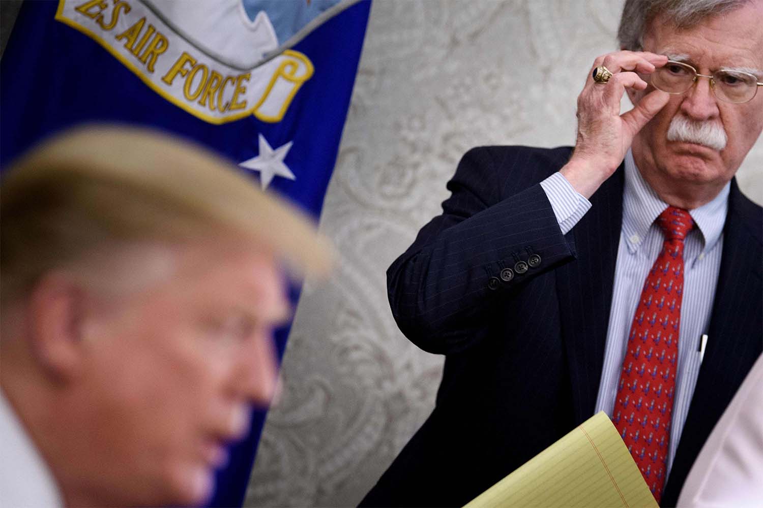 Former National Security Advisor John Bolton listening to US President Donald Trump