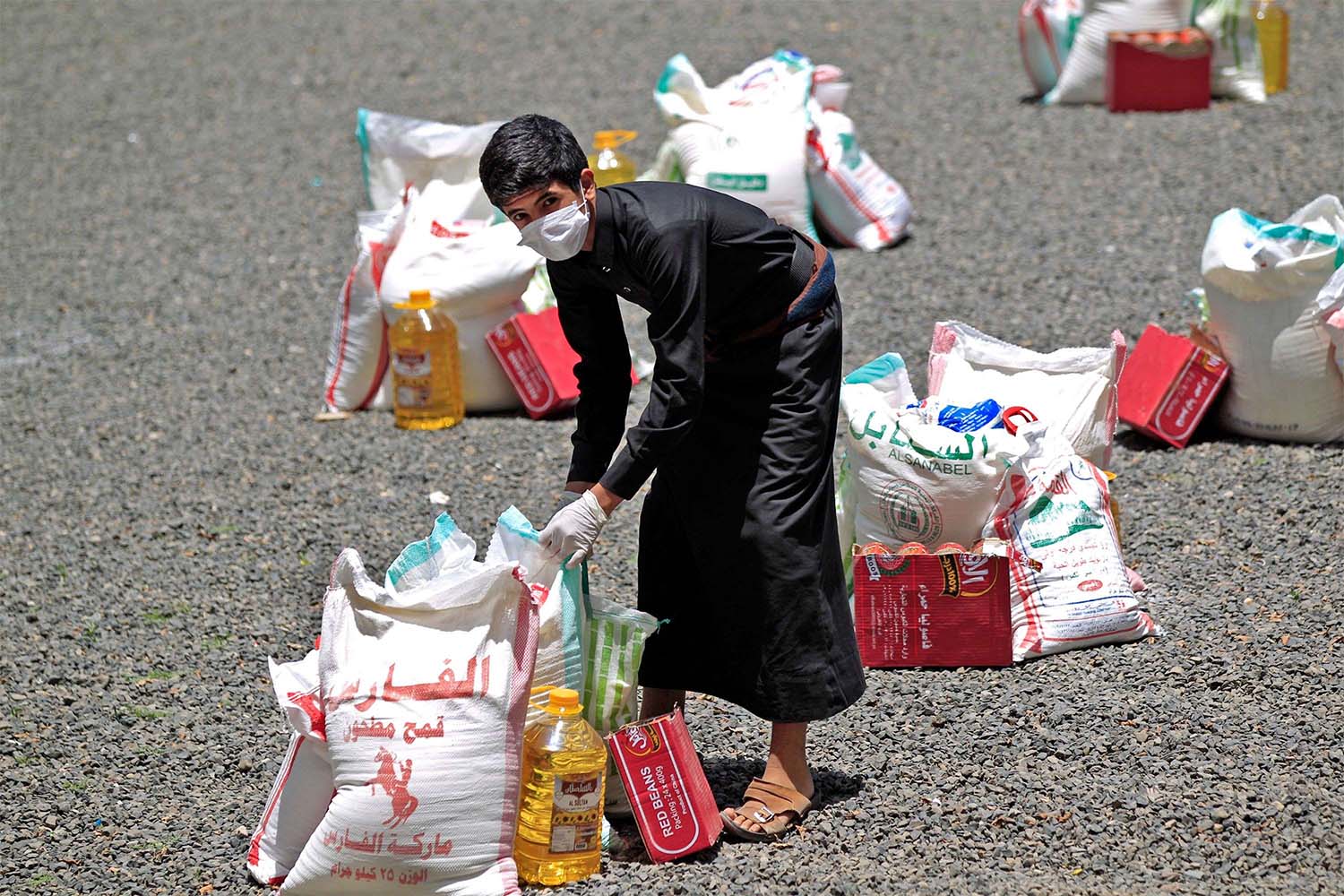 Yemeni youth carries a portion of food aid, distributed by Yadon Tabney development foundation in Sanaa