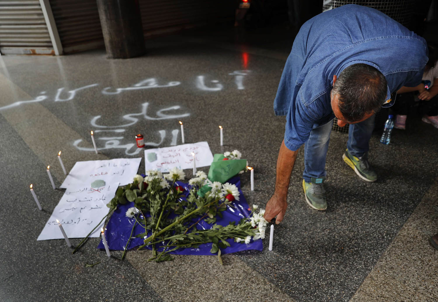 لبناني يضع زهورا على مكان انتحار لبناني قتل نفسه احتجاجا على الأزمة الاقتصادية