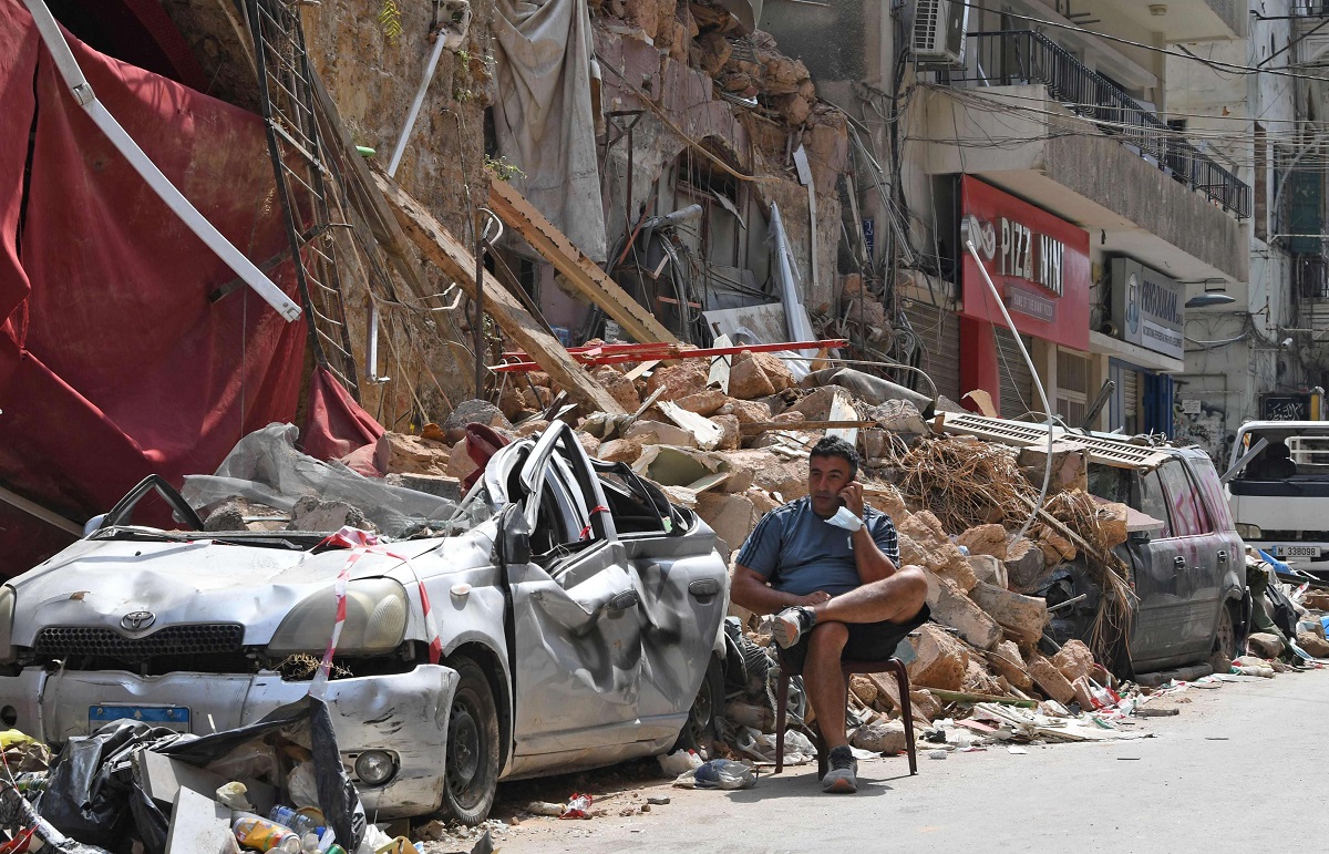  لبناني يتحدث عبر الهاتف بينما يجلس على أنقاض مبنى مدمر في حي الجميزة